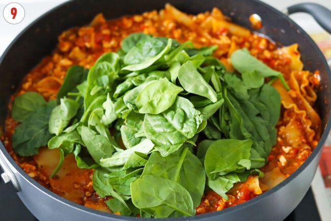 Baby spinach in pan with red pesto chicken lasagna.