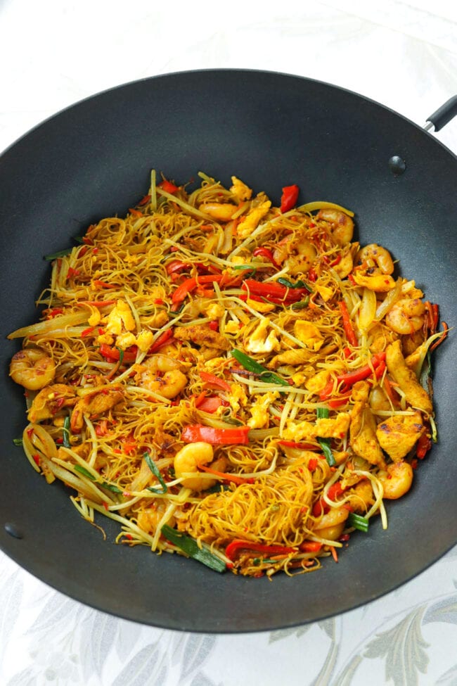 Front view of black wok with Singapore Noodles with chicken, shrimp and vegetables..