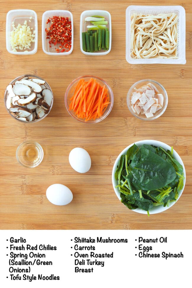 Labeled ingredients for Tofu Noodles Stir-fry with Vegetables on a wood board.