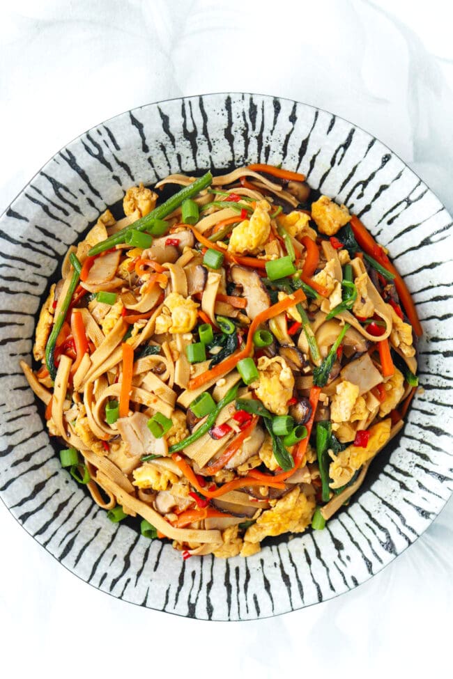 Plate with stir-fried noodles made from tofu with spinach, mushrooms, carrots, eggs, and turkey.