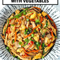 Plate with stir-fried noodles made from tofu with spinach, mushrooms, carrots, eggs, and turkey. Text overlay "Tofu Noodles Stir-fry with Vegetables" and "That Spicy Chick".