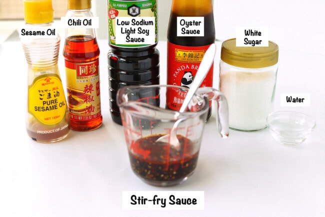 Labeled sauce ingredients for Tofu Noodles Stir-fry with Vegetables and sauce in a measuring glass with a spoon.