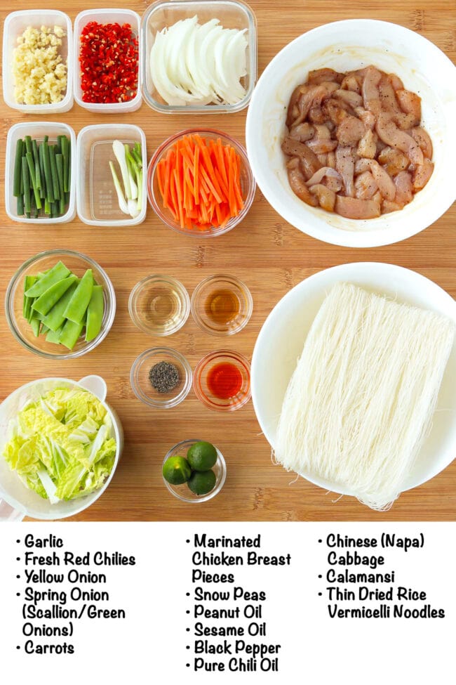 Labeled ingredients for pancit bihon with chicken on a wood board.