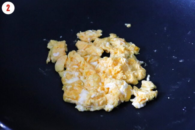 Mostly cooked scrambled eggs in a wok.