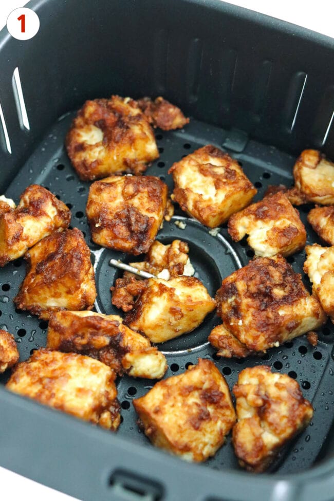 Air fryer basket with crispy air fryer tofu pieces.