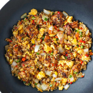 Air fryer tofu fried rice with vegetables and scrambled eggs in a wok.