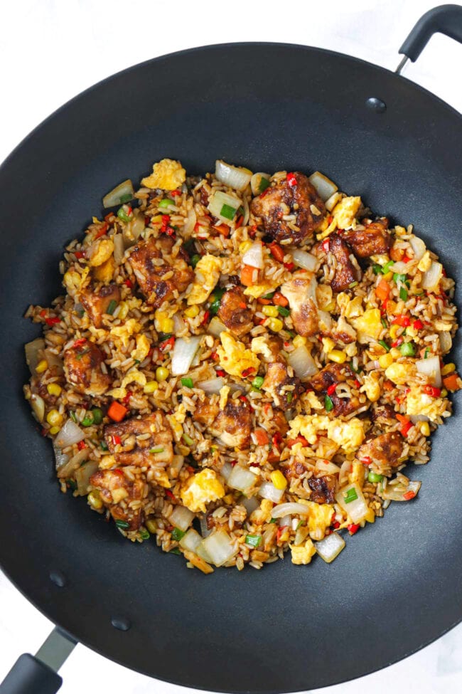 Air fryer tofu fried rice with vegetables and scrambled eggs in a wok.