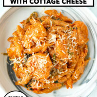 Plate with creamy kimchi pasta with shrimp topped with grated Parmigiano Reggiano cheese. Text overlay "Creamy Kimchi Pasta with Cottage Cheese", "Quick & Easy High Protein!" and "That Spicy Chick".