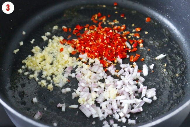Chopped garlic, shallots, and red chilies in a skillet with melted butter.