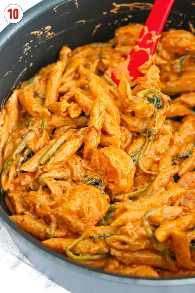 Closeup front view of pan with creamy kimchi and gochujang pasta with spinach and shrimp.