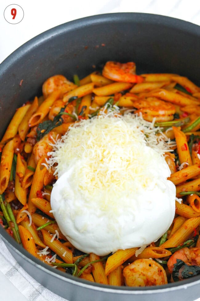 Grated parmesan and blended cottage cheese in a pan with kimchi pasta with spinach and shrimp.
