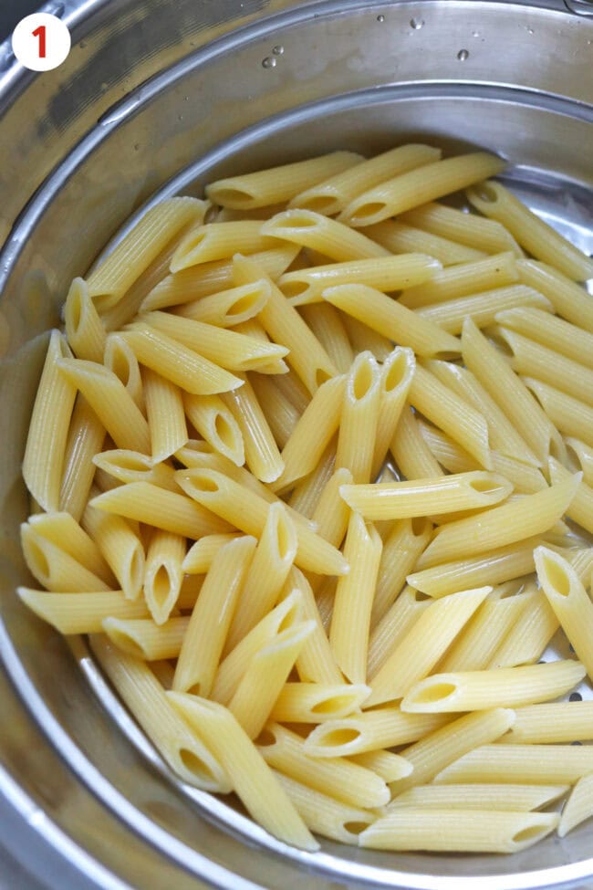 Cooked and drained penne pasta in a colander.