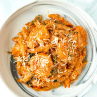 Top view of plate with creamy kimchi pasta with cottage cheese sauce and shrimp topped with grated Parmigiano Reggiano.