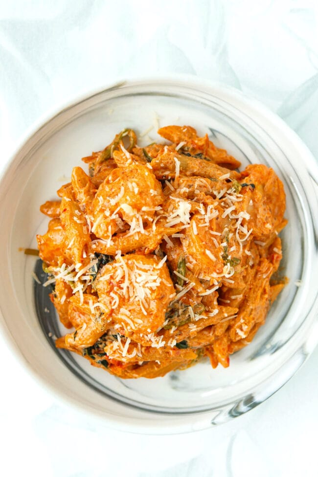 Top view of plate with creamy kimchi pasta with cottage cheese sauce and shrimp topped with grated Parmigiano Reggiano.