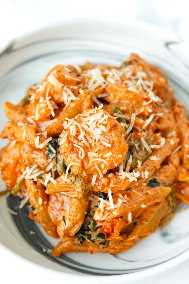 Front view of plate with creamy kimchi pasta with spinach and shrimp topped with grated parmesan.