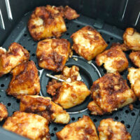 Closeup of crispy air fryer tofu nuggets in air fryer basket.