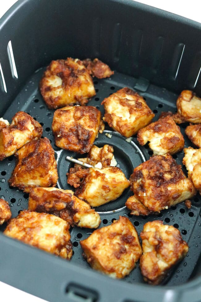 Closeup of crispy air fryer tofu nuggets in air fryer basket.