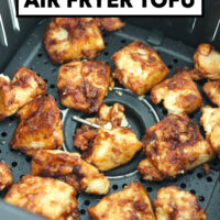 Closeup of air fryer tofu pieces in air fryer basket. Text overlay "Air Fryer Tofu" and "That Spicy Chick".