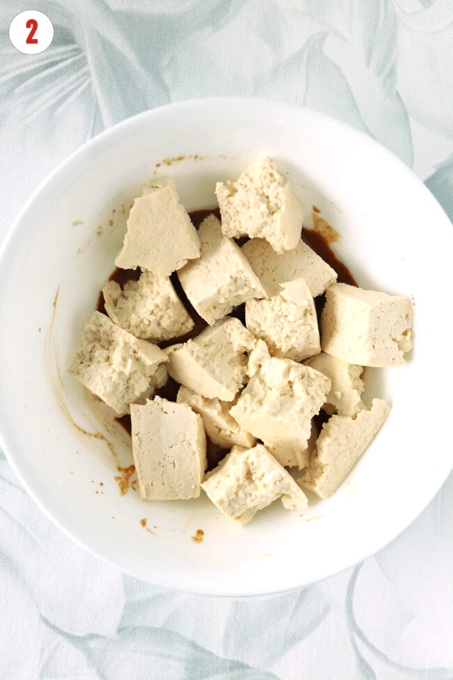 Bowl with marinade and torn tofu pieces.