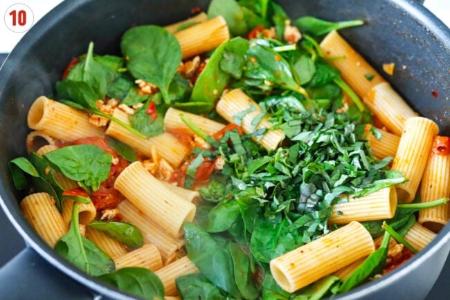 Basil and lemon juice in a pan spicy harissa rigatoni with cherry tomatoes and spinach.