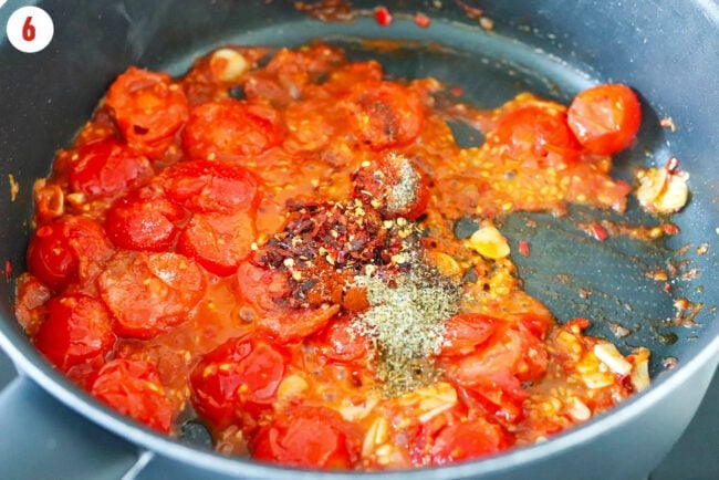 Seasonings in pan with burst cherry tomato sauce with garlic.
