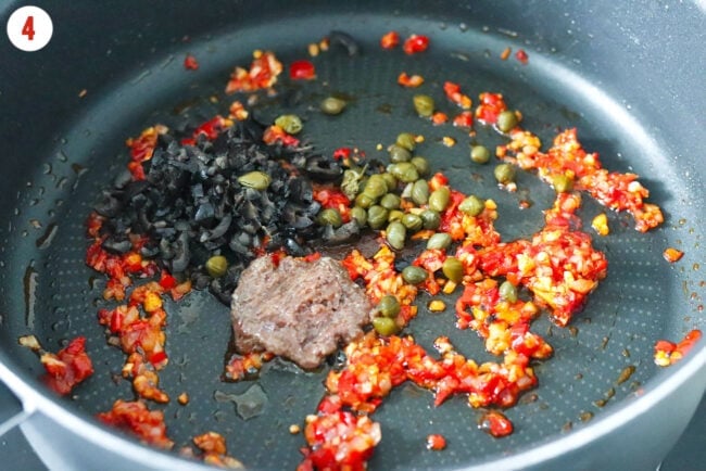 Finely chopped anchovies, olives, and capers in a pan with sautéed aromatics, Calabrian chili sauce and tomato paste.
