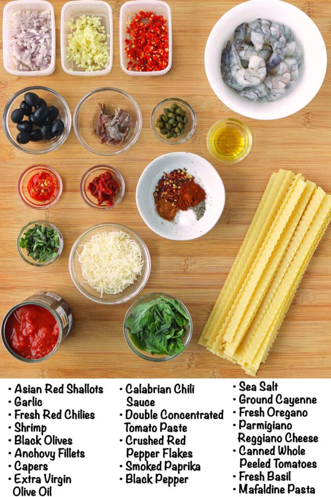 Labeled ingredients for puttanesca pasta with shrimp on a wood board.