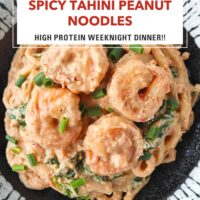 Plate with creamy tahini udon noodles with shrimp, spinach and green onions. Text overlay "Spicy Tahini Peanut Noodles" and "High Protein Weeknight Dinner!!".