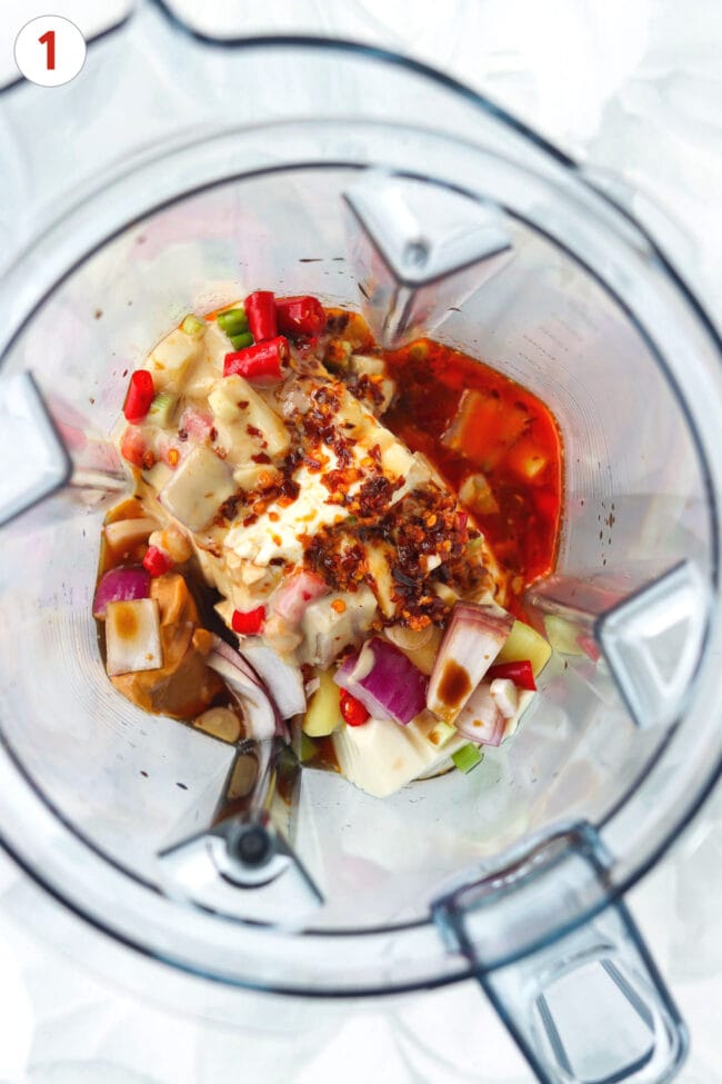 Ingredients for creamy silken tofu tahini and peanut butter sauce in a blender jug.