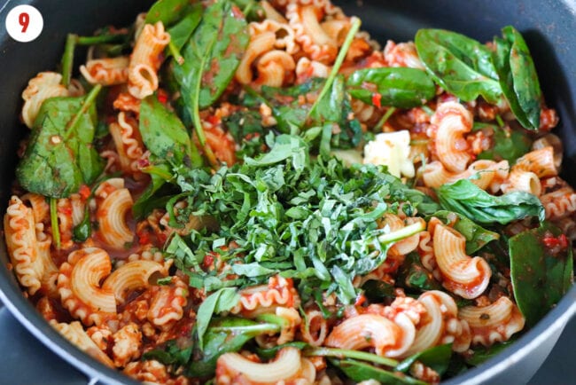 Sliced fresh basil added to tomato pasta with spinach.