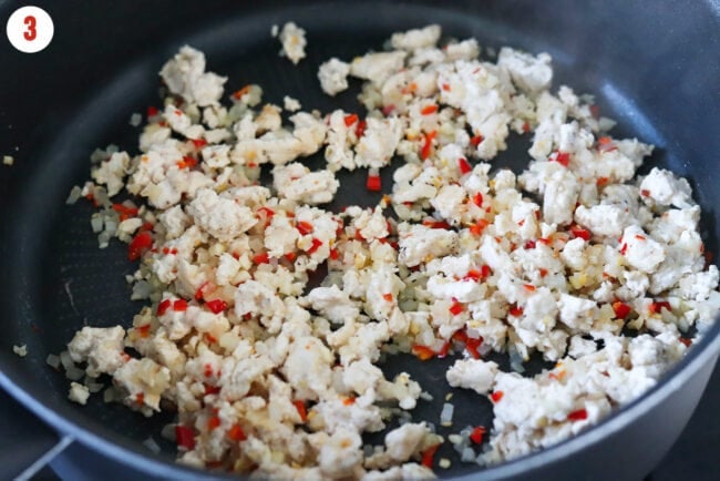 Cooked ground chicken, fresh chilies, garlic and onion in a pan.